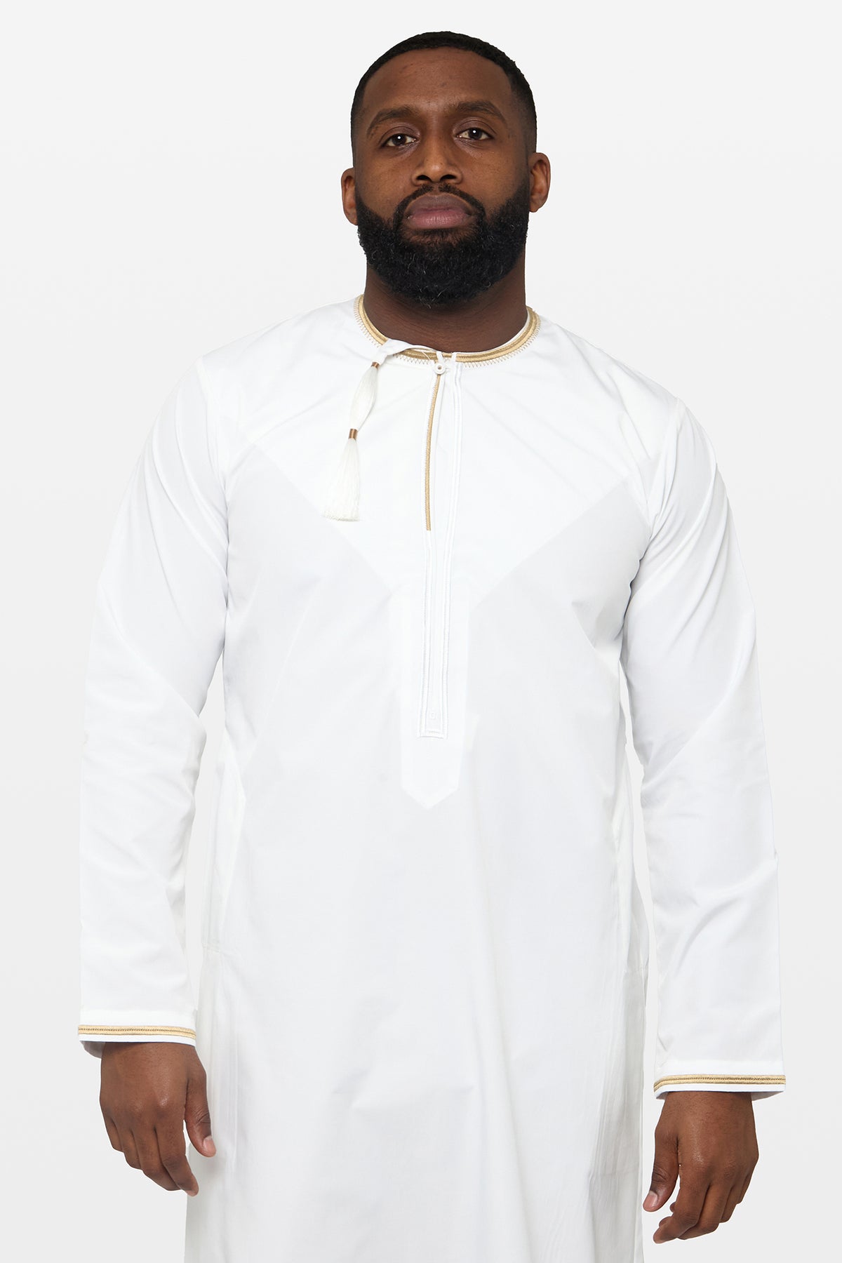 Model wearing a white and gold Omani thobe with a tasselled neckline